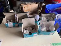 Wide view of four open cardboard boxes containing various lightbulbs separated by type.