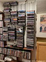 Photo showing multiple DVD movies organized on wall-mounted wire racks and on shelving below.