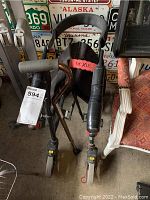 Front view of Nexus folding walker showing padded seat, armrests and wheels, along with adjacent adjustable metal cane with foam grip.