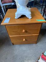 Front view of the wood nightstand with two drawers, showing scratches and general condition.