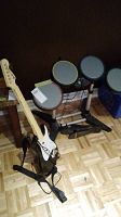 Guitar controller and electronic drums setup on floor, showing overall items in lot.