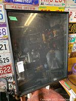 Front view of large shadow box display frame, showing reflective glass and black frame.