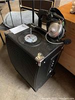 Top and side view of the speaker with attached LG headphones showing the microphone boom and cushioned ear pads.