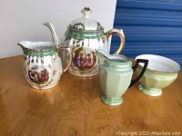 Four porcelain items including a Bavaria-style teapot and creamer with painted classical figurative scenes and gold accents, plus a green and cream creamer and bowl likely from Palt China.