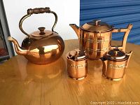 Image showing copper kettle with wooden handle alongside the copper teapot, sugar container, and creamer.