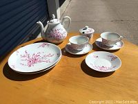 View of full set with teapot, sugar bowl, two cups with saucers, and two plates showing overall items and pattern