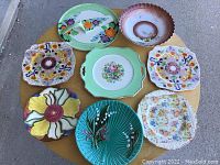 Seven assorted floral-themed decorative china plates arranged on a table.