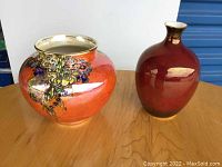 Photo of both Grimwades Crown Devon vases on wooden surface, showing one large orange decorated vase and one smaller maroon vase with gold trim