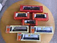 Seven boxed train models arranged on round wooden table