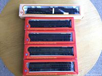 Five IHC HO scale model train miniatures displayed in original boxes, placed on a wooden table.