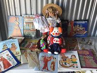 Full overview of all items displayed, including dolls, plush toys, paper dolls, booklets, and a dress