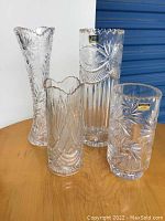 Set of four Polonia crystal vases arranged on table showing varying heights and patterns.