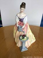 Front view of Royal Doulton Alexandra figurine showing woman watering flowers on pedestal