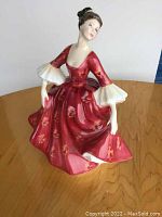 Front left angled view of the Royal Doulton Stephanie figurine showing red floral dress and white ruffled sleeves.