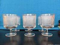 Front and side view of 6 clear textured ripple wine glasses by Ferm Living, showing their height and design details.