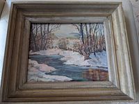 Oil painting showing a winter scene with a stream and trees in a textured vintage wooden frame.