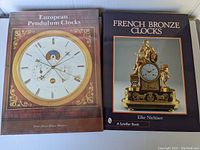 Two large hardcover books titled 'European Pendulum Clocks' and 'French Bronze Clocks' showing front covers with detailed clock images.