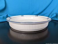 Side angle showing the pie dish's ribbed exterior and decorative floral rim pattern on white ceramic.
