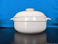 Front and side view of white ceramic tureen with lid showing glossy surface and integrated handles.