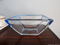 Front side view of the square glass bowl showing the blue rim and clear glass body.