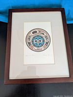 Framed Indigenous art print with circular design and artist's signature visible below artwork, mounted on white mat with dark wood frame.
