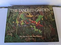 Front cover of the art book titled 'The Tangled Garden' showcasing colorful garden artwork and text by Paul Duval.