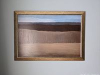 Full frontal photo of framed art print showing horizontal sections of muted colors resembling a landscape with sky, earth, and middle layer of dark brown brush or hill.