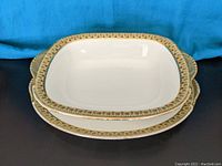 Top view of two nested Limoge handpainted china pieces showing ornate patterned gold and multicolored borders on white china.