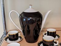 Front view of coffee pot with two demitasse cups and saucers