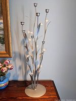 Metal flower sculpture with multiple candle holders on slender stems, showing full view including base and flower details