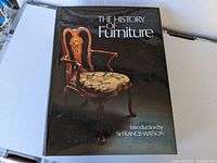 Front cover of 'The History of Furniture' showing an antique armchair with ornate woodwork on a black background and the introduction credit to Sir Francis Watson.