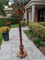 Full view of the tall solid wood coat rack showing the octagonal base, turned central post, and multiple hooks at the top.
