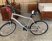 Side view of silver Marin 26" bicycle with kickstand and hanging helmet