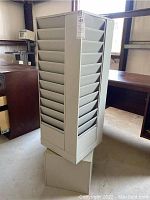 Front diagonal view of the metal rotating brochure rack showing its multiple slots and square base