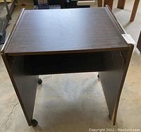 Front angle view of laminate rolling cart showing missing drawer and wheels.