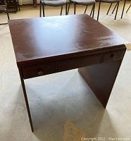 Side angle view of Palliser work site computer desk showing brown laminate surface and drawer with brass-tone knobs.
