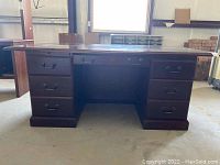 Front view of the dark wood and laminate executive desk showing six pedestal drawers with metal pulls and a central kneehole space.
