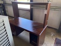 Sauders laminate desk, medium wood-tone finish, showing desktop and right side open shelving with visible damage and scuffs