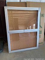 Full view of the lockable display case showing the corkboard interior on two panels within the silver aluminum frame and glass front.