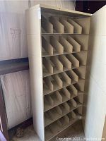 Front view of beige metal open file cabinet showing seven rows of compartments with vertical dividers.