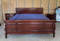Frontal view of king bed frame and mattress showing headboard, footboard and side rails in dark wood finish