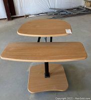 Front view of mobile sit/stand desk showing wood veneer top and keyboard tray surfaces with curved edges.