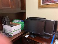Six computer monitors and multiple keyboards with some cables on a desk and shelf.