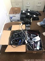 Boxes containing corded Panasonic hybrid phones, cords, and cables scattered and piled.