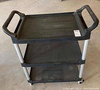 Front and top view of Rubbermaid three tier rolling cart showing handles and top shelf surface.