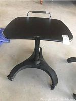 Front view of black ergonomic curved rolling table top and base with three caster wheels.