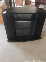 Full view of black side cabinet showing front glass door, curved base and overall shape.