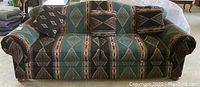 Full front view of a three-seat sofa upholstered with southwestern geometric patterned fabric, including two matching pillows.