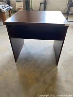 Front view of the laminate side table/desk showing the missing drawer and damaged surface.