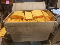 Large cardboard box labeled Model: #0 QTY: 1000 pcs containing stacked yellow padded envelopes
